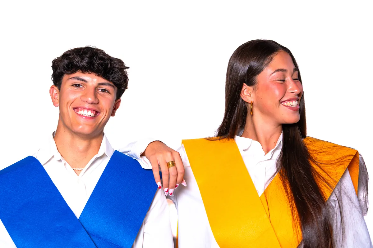 Dos estudiantes riendo con becas de graduación de colores sobre fondo blanco